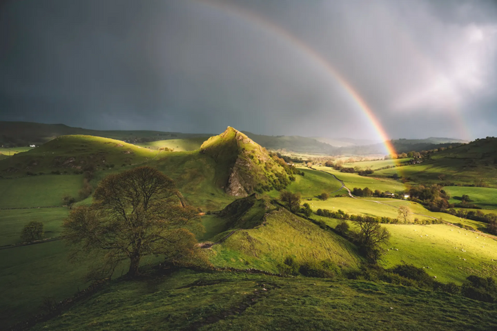 A rainbow over a green hillside